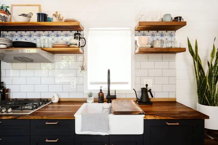 Petite cuisine avec cache-brûleurs en bois sur la cuisinière, transformant la surface en plan de travail supplémentaire pratique