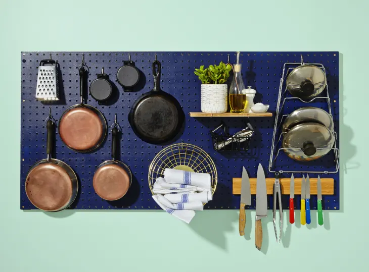 Rebord de fenêtre de cuisine utilisé comme étagère décorative avec plantes vertes et livres de recettes, ajoutant couleur et charme à un petit espace