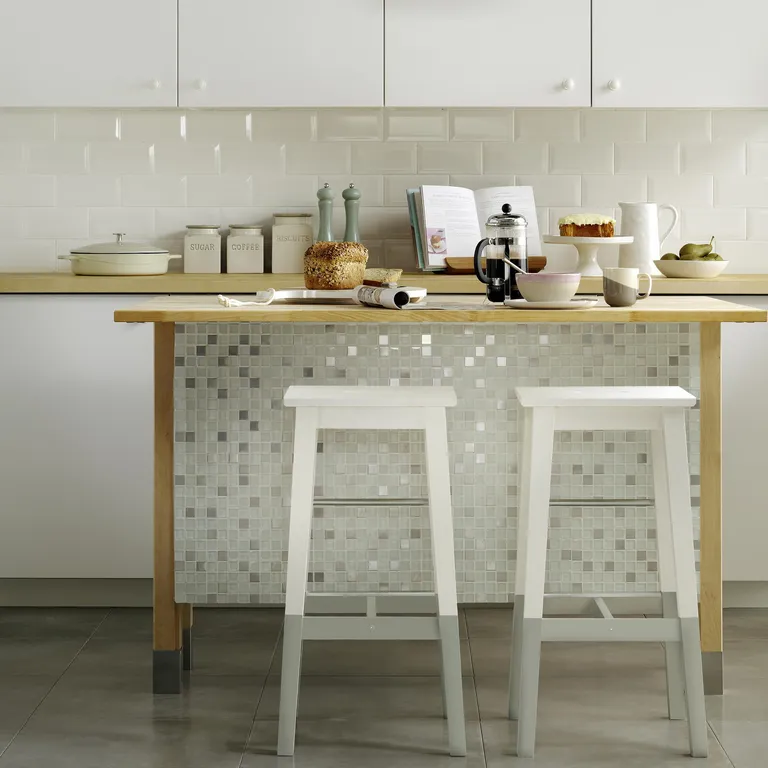 Tabourets de bar IKEA Nilsolle personnalisés avec peinture blanche et pieds gris, autour d’un îlot central dans une petite cuisine fonctionnelle